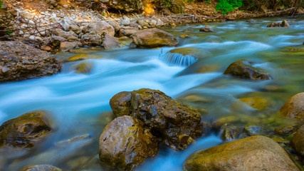 Fototapeta na wymiar emerald river rushing over the stones in a mountain canyon, long exposure image