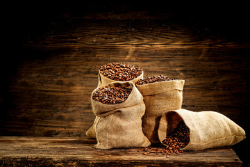 Fresh coffee in sack and wooden wall background 
