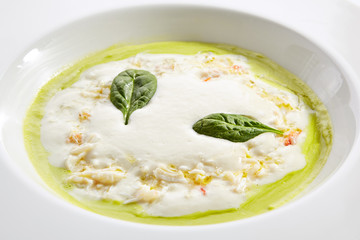 Green pea cream soup with mozzarella mousse top view