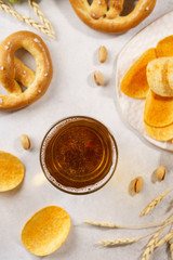 A glass of lager beer with german pretzels and chips.