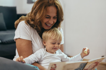 grandmother with her grandson reading picture book together at home