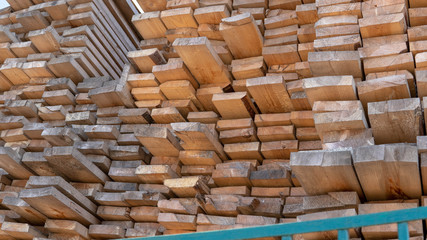Wooden boards, lumber, industrial wood, timber. Pine wood timber stack of natural rough wooden boards on building site. Industrial timber building materials