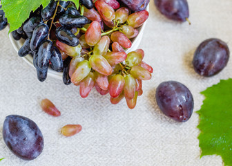 Autumn composition. Grape and plums on the white bowl