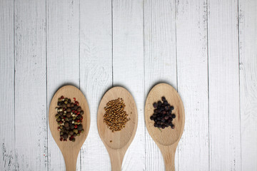 juniper, cumin and peppercorn mix in serving spoons on wooden background. Image contains copy space
