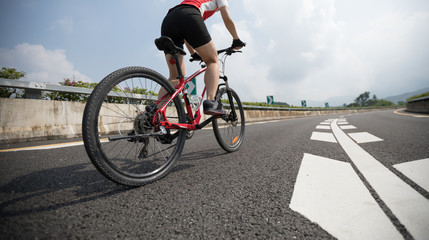 Fototapeta premium Woman cyclist riding Mountain Bike on highway