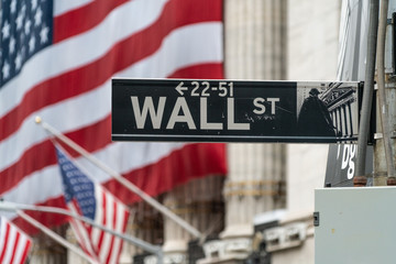 Wall St. Street Sign With Large Financial Structure In Background And American Flag