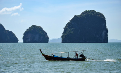 Fototapeta na wymiar Silhouette of a man driving a long-tail boat in Phang Nga Bay, Thailand.