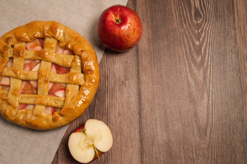 Homemade cake. Delicious Apple pie, red apples, linen napkin on wooden background.