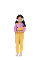 little Asian child girl in pink-yellow dungarees with headphones to enjoys listening music by smartphone isolated on white background. Full length in studio shot.