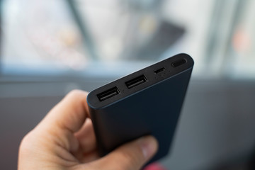 Man is holding the power bank a an the charger. Powerbank in hand. Power-saving device for smartphone and other devices. Helping to charge your phone.