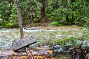 Sign for ford river crossing on Conundrum Creek Trail in Aspen, Colorado in 2019 summer in forest woods with strong current