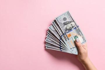 Top view of female hand holding a fan of one hundred dollars on colorful background. Loan concept. Prosperity concept with copy space - obrazy, fototapety, plakaty