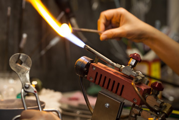 Glassblower. Glass on fire. The work of the master on a propane burner with hot glass.