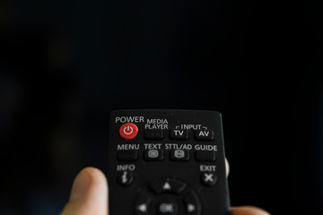 Close up on a man's hand with the remote control want switch on the TV and presses the button on the remote control. Remote control in hand closeup.