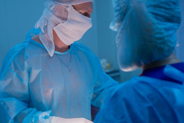 Fototapeta premium Children's surgeons perform urological surgery. A man and a woman in a mask, and a blue sterile gown, in the operating room.
