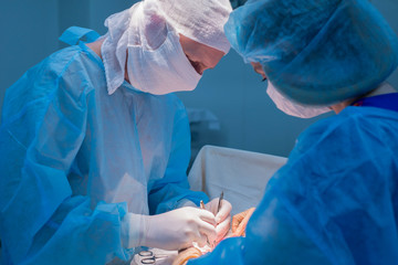 Children's surgeons perform urological surgery. A man and a woman in a mask, and a blue sterile gown, in the operating room.