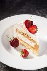 a piece of delicate cake, with slices of sliced strawberries, on a white plate on a white and gray background