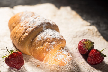 French croissant with strawberries. Rustic style, dark gray abstract background
