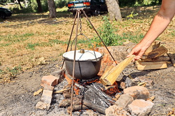 Cooking barbecue and fish soup on a bonfire on a picnic outside the city. Summer, 2019.