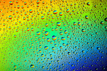 closeup of water droplets on a glass. Rainbow background, colorful abstract pattern.