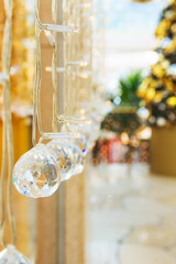 Elegant Christmas New Year decorations crystal balls sparkling in bokeh lights. Festive fir tree in the background magic holiday atmosphere