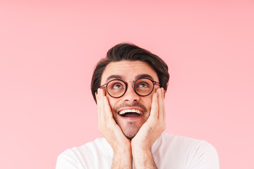 Image of brunette happy man wearing eyeglasses looking upward at copyspace and propping his head