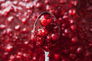 raspberry jam is kept with a metal spoon, shallow depth of field