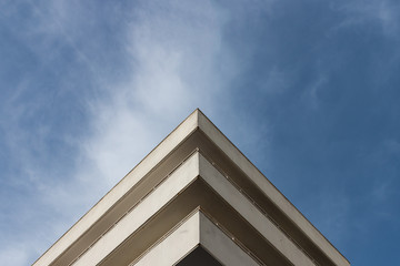 Fototapeta na wymiar White triangular building under blue and cloudy sky