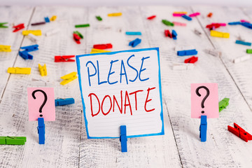 Conceptual hand writing showing Please Donate. Concept meaning Supply Furnish Hand out Contribute Grant Aid to Charity Crumbling sheet with paper clips placed on the wooden table