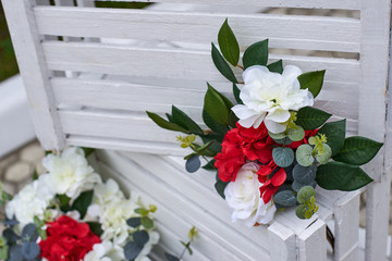 Fragment of outdoor wedding decorations, box decorated with red and white flowers.