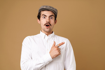 Image closeup of shocked mustached man wearing hat pointing finger at copyspace
