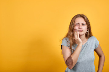 brunette girl in gray t-shirt over isolated orange background shows emotions