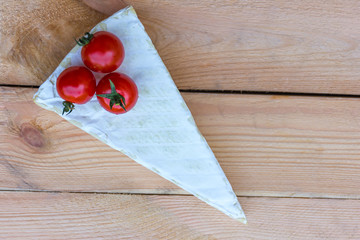 Cheese and cherry tomatoes on wooden background. 