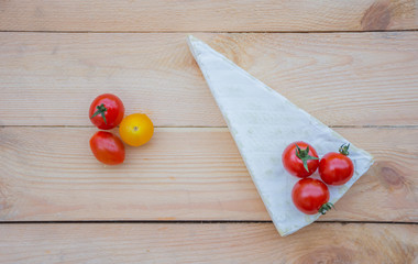 Cheese and colorful red, orange and yellow cherry tomatoes on wooden background. 