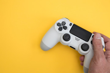 Video games man playing white gaming controller in hands isolated on yellow color background top view