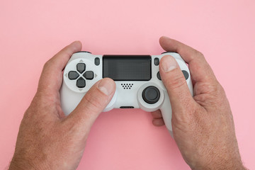 Video games man playing white gaming controller in hands isolated on pink color background top view