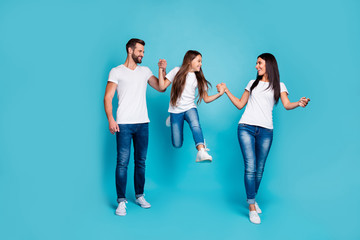Fototapeta premium Full size photo of daddy mommy and small lady going and jumping together wear casual outfit isolated blue background