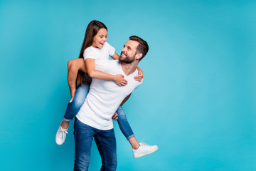 Portrait of cheerful man holding his kid with brunette hairstyle piggyback wearing white t-shirt...