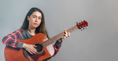 Fototapeta premium Portrait of a young pretty woman with an acoustic guitar in her hands. Copy space