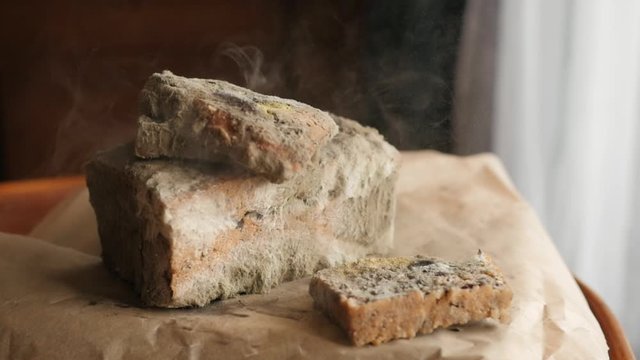 slice of bread falling on moldy bread, particles of mold slow motion, swirl, floating