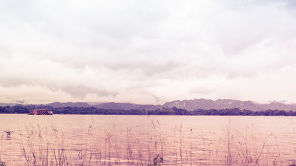 Fototapeta premium Green meadow with river and fog over mountains in Kanchanaburi Thailand
