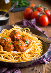 Delicious spaghetti with meatballs in tomato sauce on dark background, italian cuisine