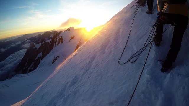 Group of climbers reaches the top of mountain peak. Climbing and mountaineering sport.