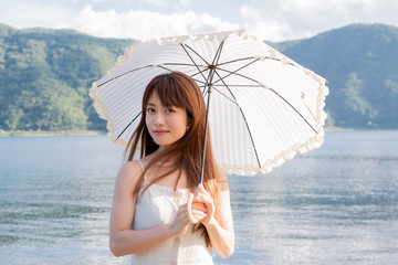 日傘を持って湖畔に立つ女性