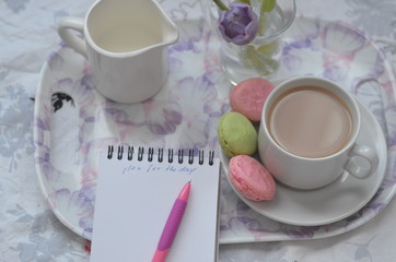 tray with paper sketchbook, smartphone and spring flowers on pink bedding. Relaxing, or working, or writing diary or blog in bed at home.