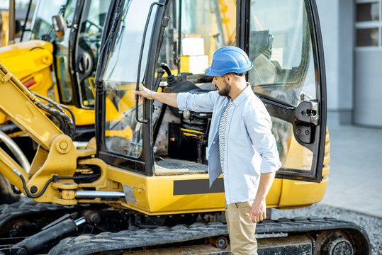 Handsome builder trying escavator while buying a new heavy machinery for construction on the open ground of the shop