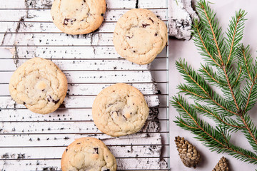 Ð¡hocolate Chip Cookies on cooling rack and on birch bark decorated fir branches and cones. Fast and easy scandinavian pastry. Cozy winter treat. Hygge. Fika