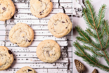 Сhocolate Chip Cookies on cooling rack and on birch bark decorated fir branches and cones. Fast and easy scandinavian pastry. Cozy winter treat. Hygge. Fika