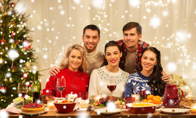 holidays and celebration concept - happy friends having christmas dinner at home over snow