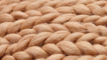 Merino wool handmade knitted large blanket, super chunky yarn, trendy concept. Close-up of knitted blanket, merino wool background. designer blanket made of beige smoky wool
